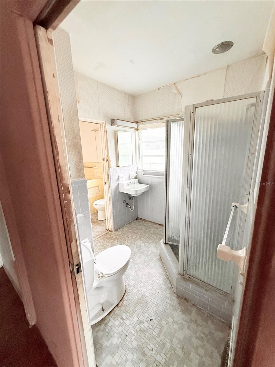 Vintage-style primary bathroom with walk-in shower, original tilework, and functional layout ready for renovation or restoration to your personal taste.