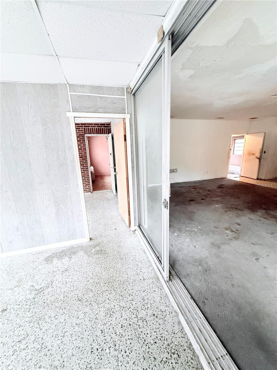 Enclosed Florida room offers additional flexible living space with terrazzo flooring and sliding glass door access to the main living area. Ideal for a sunroom, office, or bonus entertaining space.