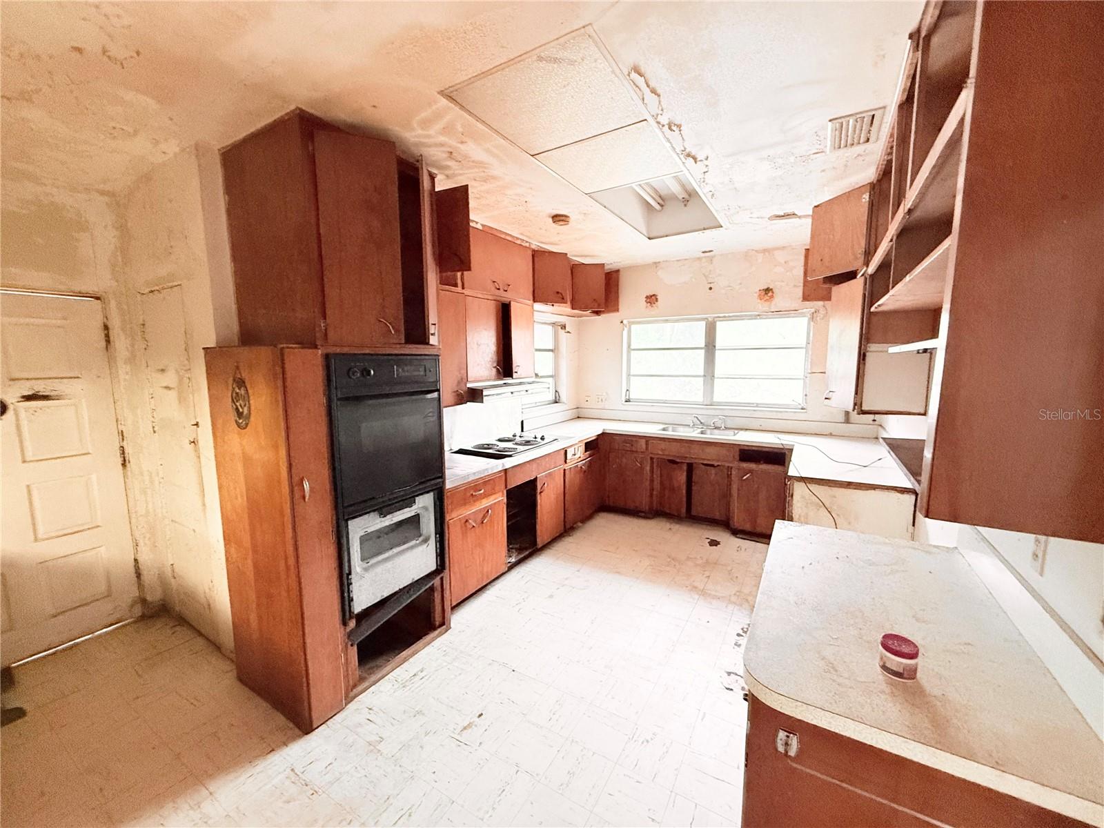 Original kitchen with extensive cabinetry, wraparound counter space, and functional galley layout. Excellent renovation opportunity to create a modern chef-inspired kitchen.