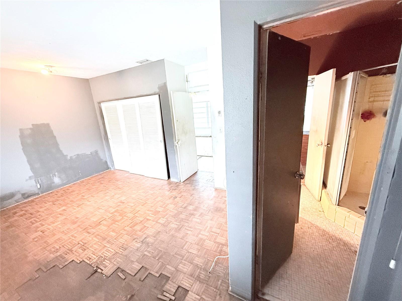 Private bedroom suite layout with parquet flooring, closet storage, and direct access to bathroom area. Ideal setup for a primary suite redesign.