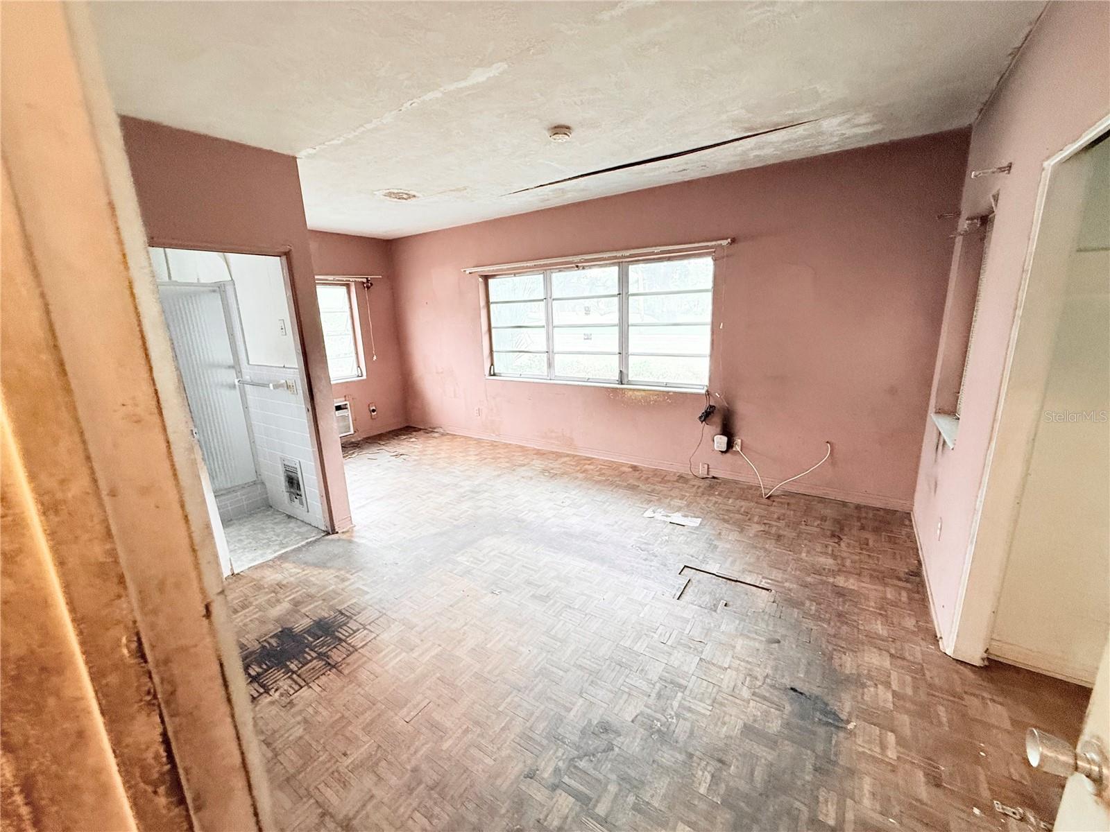 Additional spacious bedroom featuring parquet flooring, ample wall space, and natural lighting. Perfect opportunity for updating into a comfortable guest room or office.