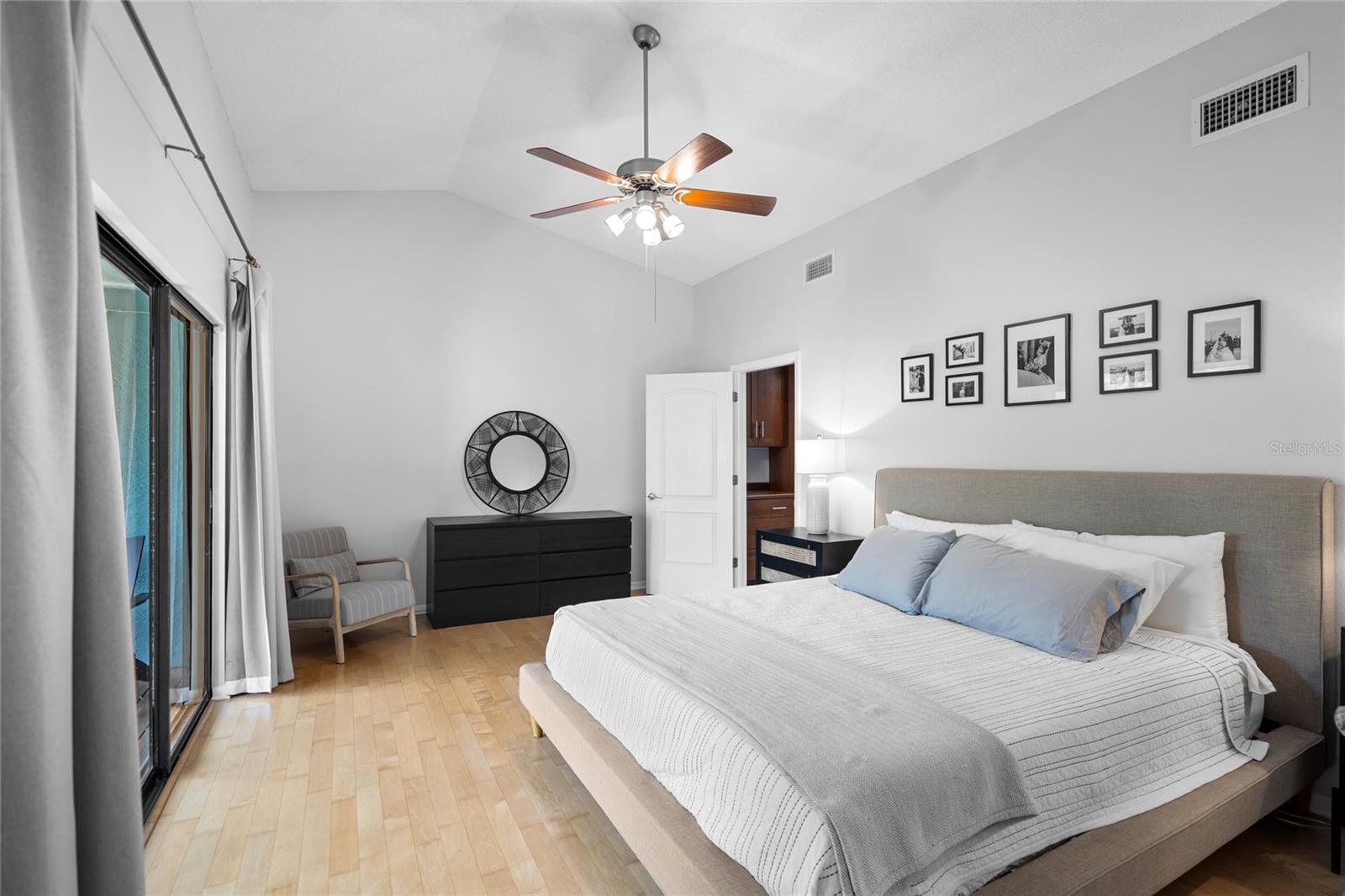 Upstairs Primary Bedroom with vaulted ceilings and view of preserve and a screened porch terrace with glass sliders