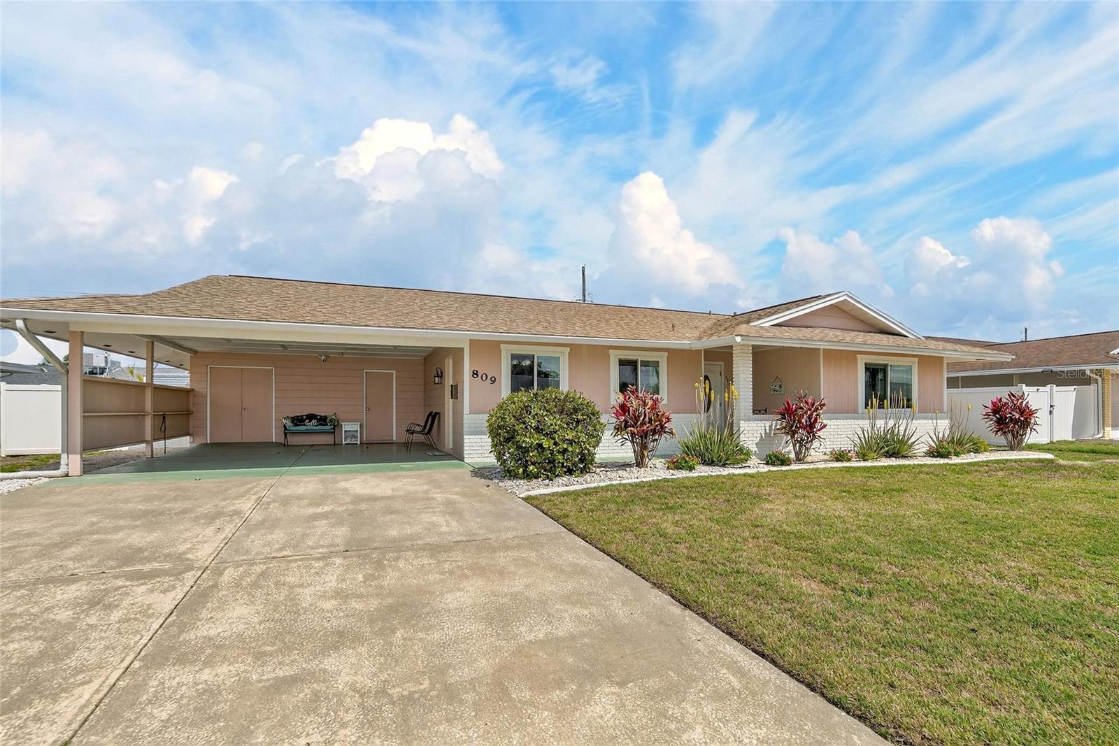 Carport with double doors leading to golf cart storage and single door to laundry room