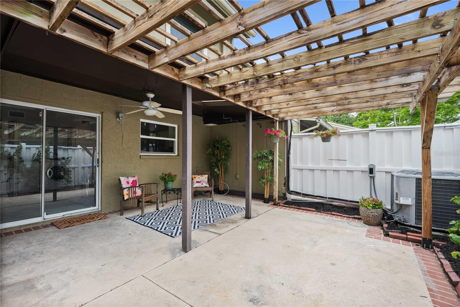 Half covered patio with pergola, completely fenced in. Fan, water, and storage closet.