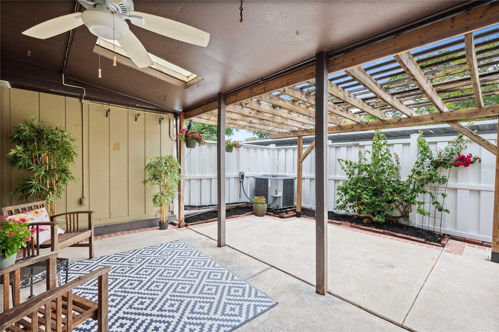 Half covered patio with pergola, completely fenced in. Fan, water, and storage closet. private gate leads to covered carport.