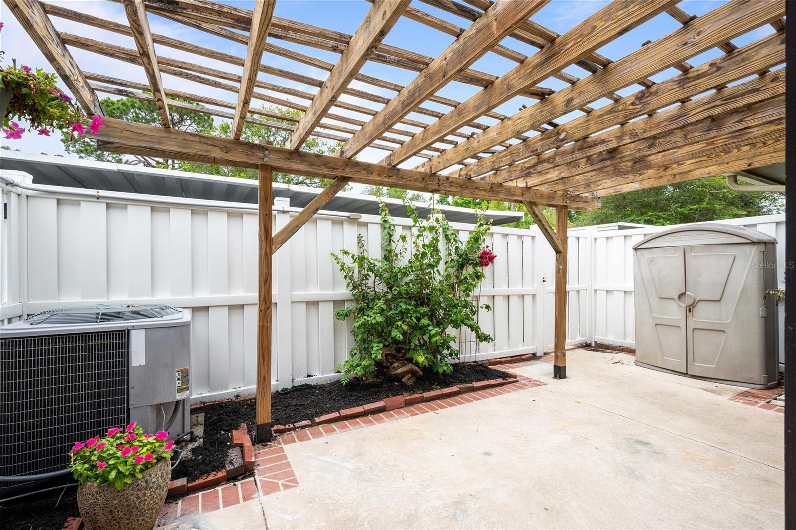 Half covered patio with pergola, completely fenced in. Fan, water, and storage closet. private gate leads to covered carport.