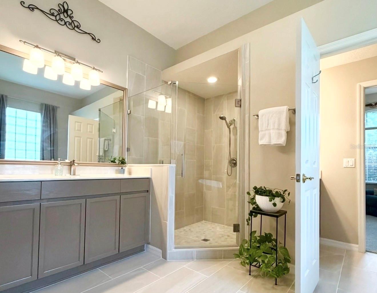 You'll love the two separate vanity sinks, oversized & frameless walk-in shower with a bench, and updated tile floors and lighting.