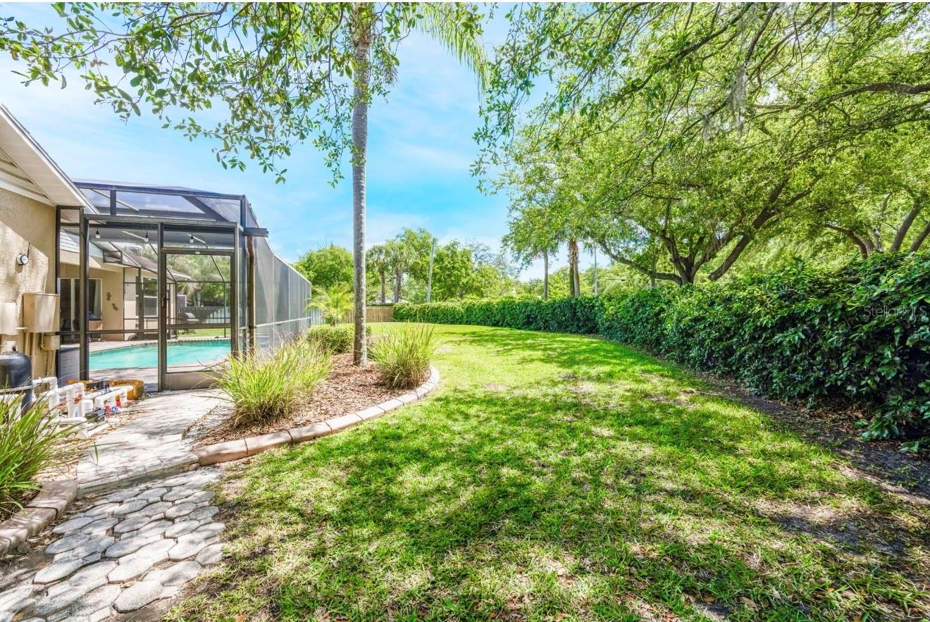 The yard backs up to a concrete wall covered with green foliage.