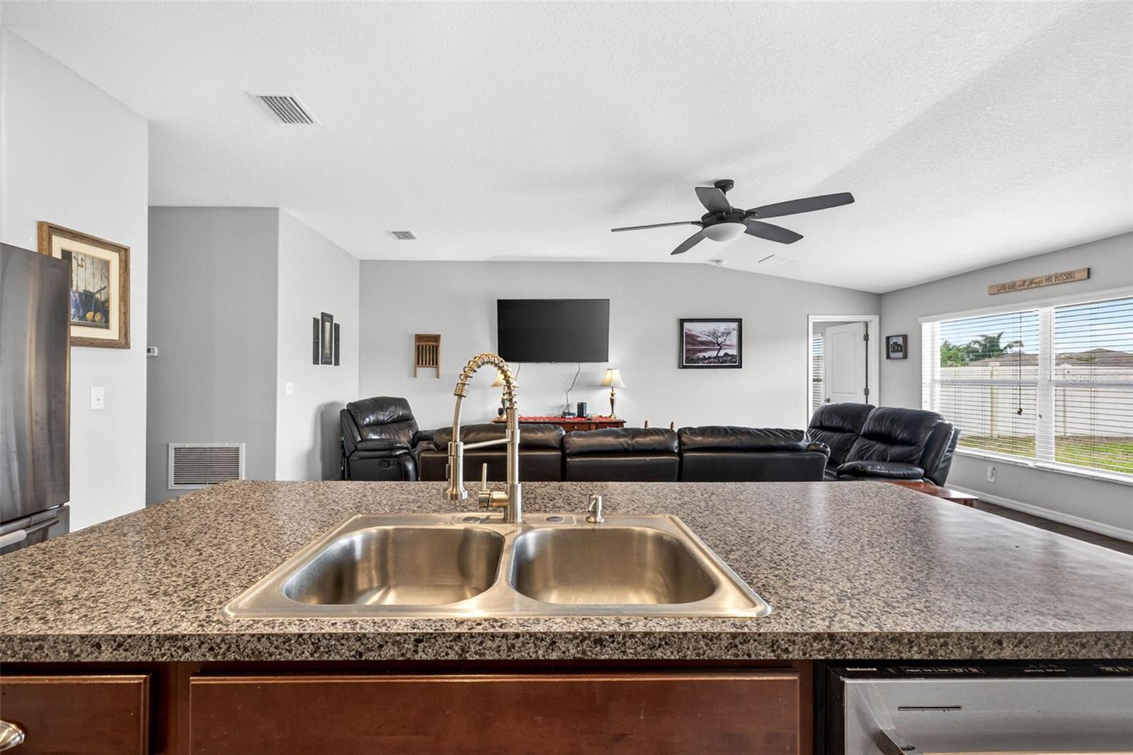 Double kitchen sink in island that overlooks main living area and views of the back yard through the large picture windows