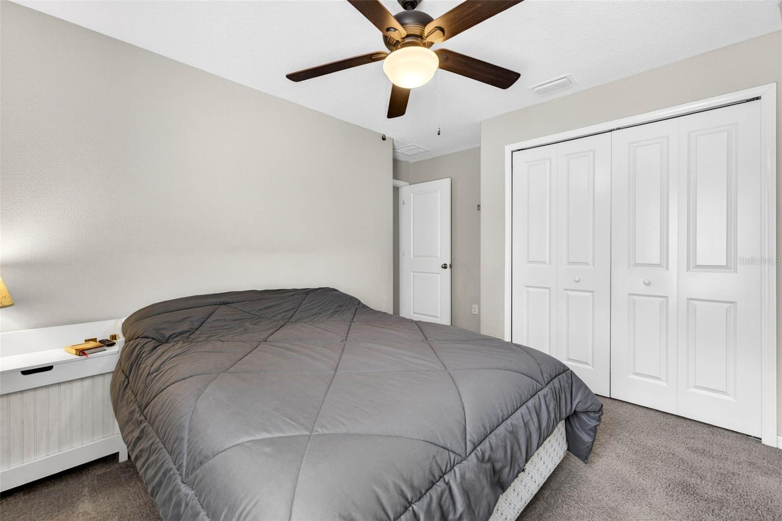 Secondary bedroom with built in closet and ceiling fan
