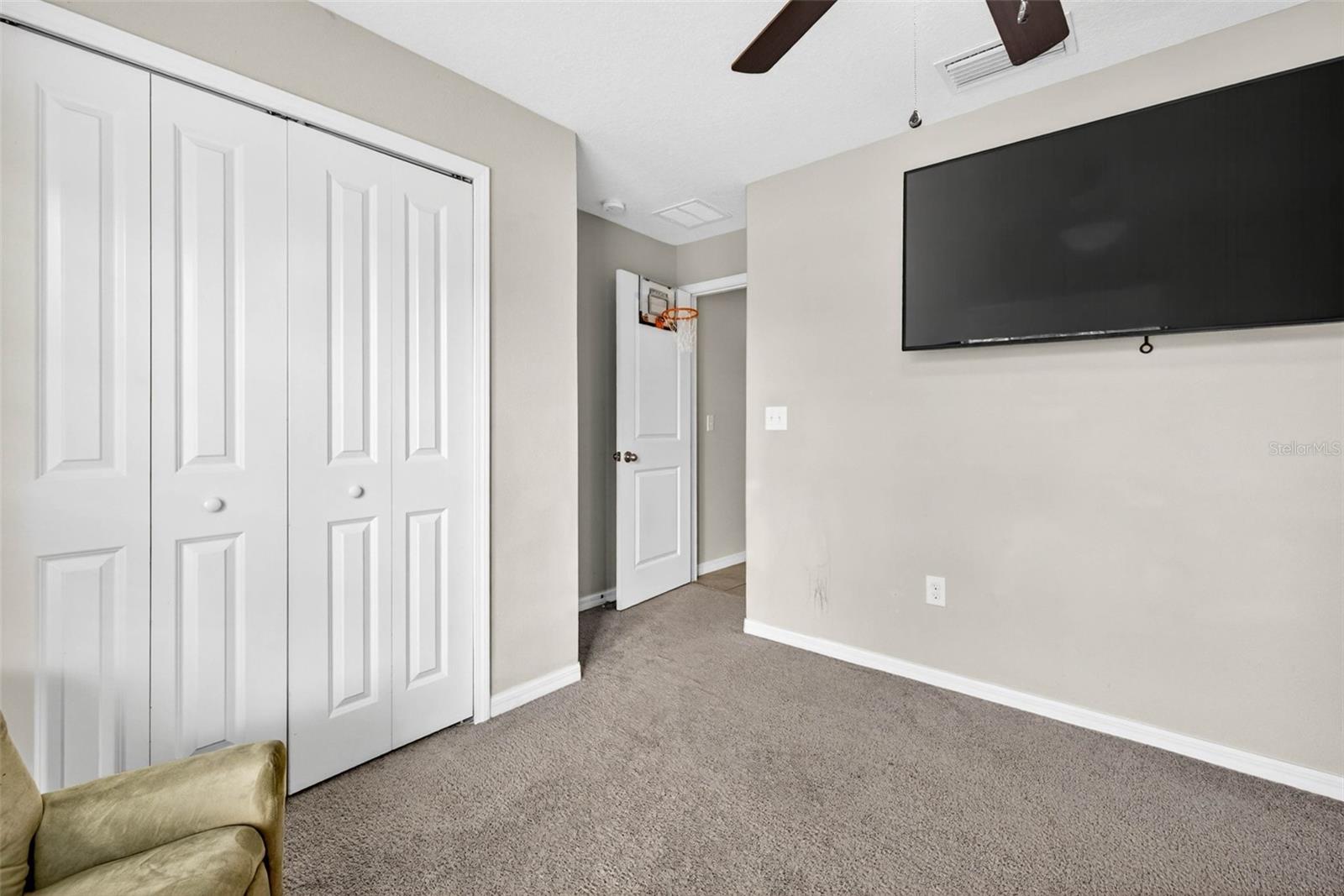 Secondary bedroom with built in closet and ceiling fan