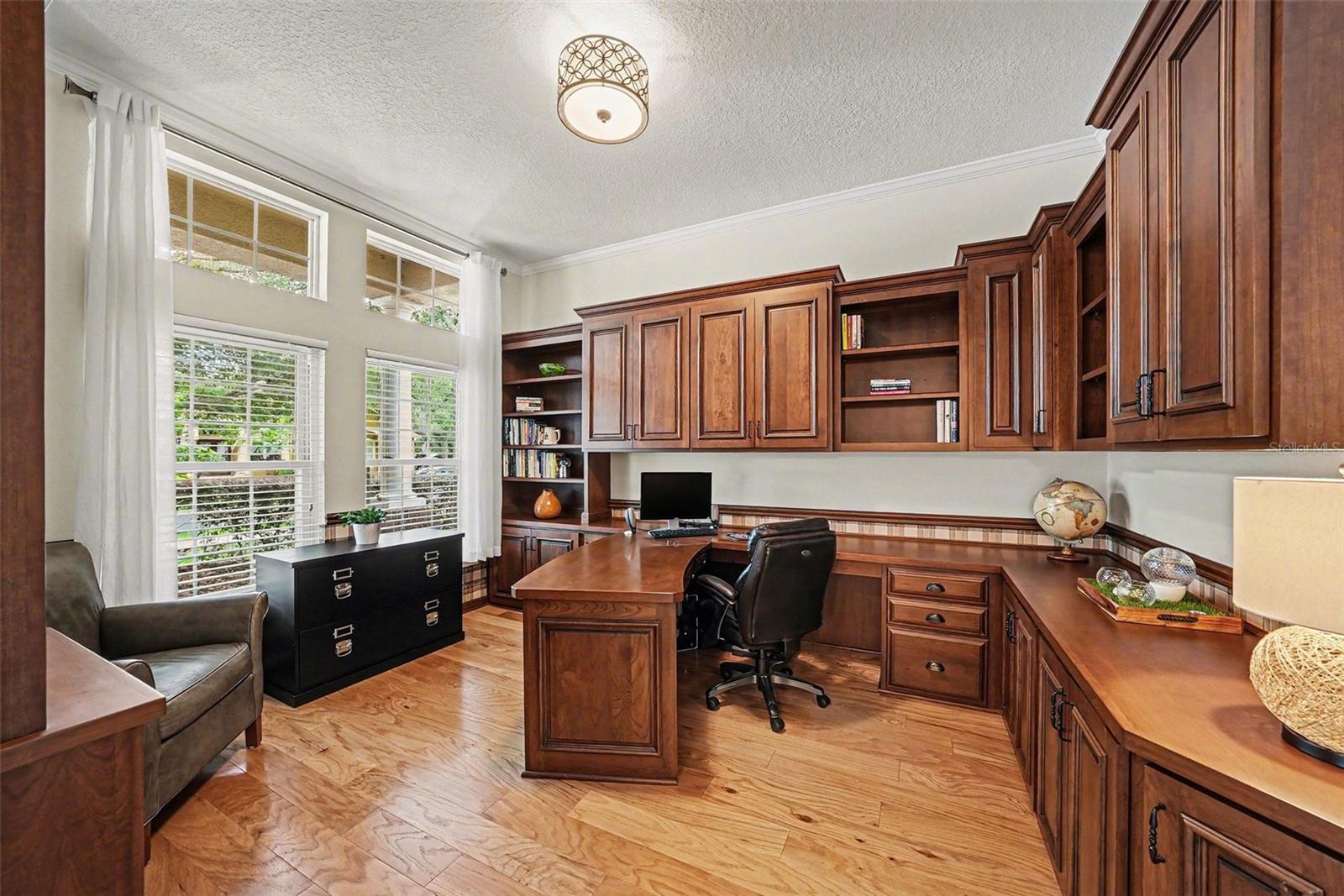 Office with custom built-in wood desk and cabinets.