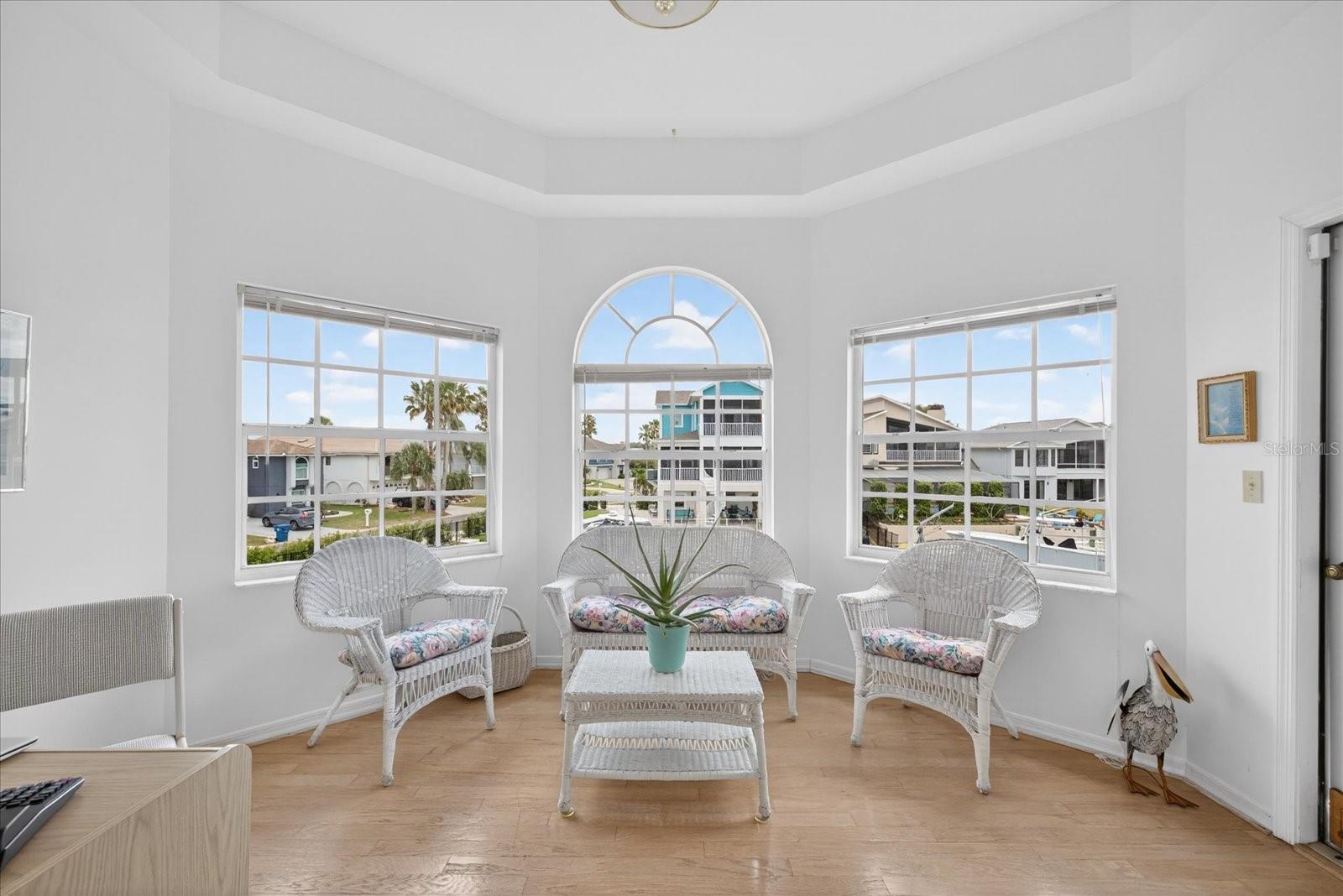 Alcove off primary suite with water views and door to screened balcony deck.