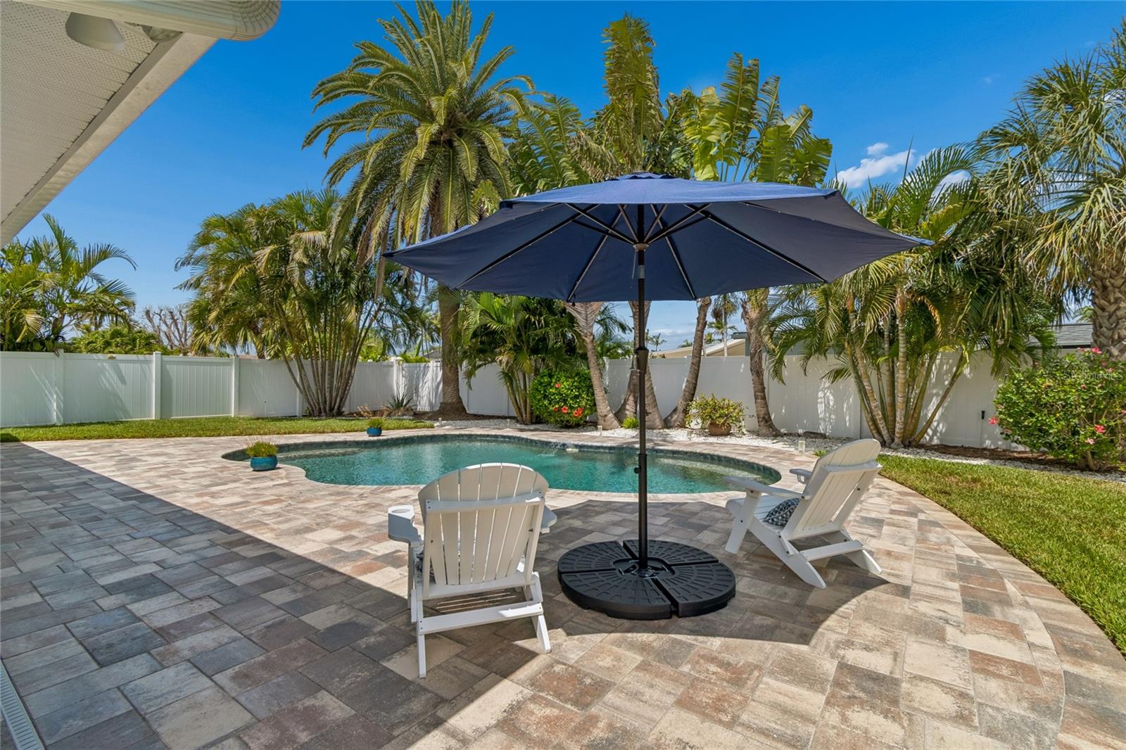 Low-maintenance, saltwater pebble-finish pool, tropical blooms, palms & pavers