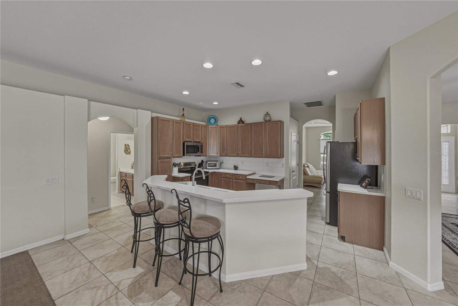 Bright, open-concept kitchen flowing into a cozy breakfast nook and spacious family room, perfect for everyday living and entertaining with direct access to the pool.