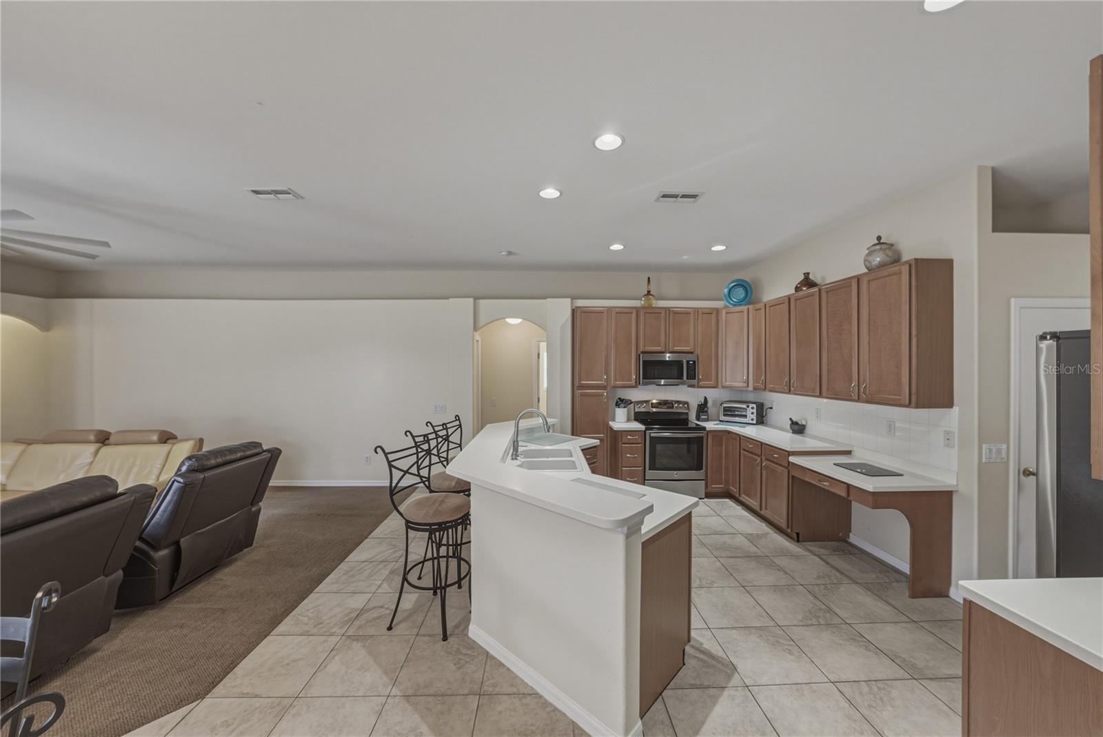 Bright, open-concept kitchen flowing into a cozy breakfast nook and spacious family room, perfect for everyday living and entertaining with direct access to the pool.