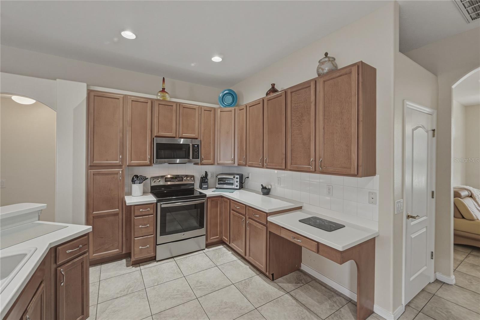 Bright, open-concept kitchen flowing into a cozy breakfast nook and spacious family room, perfect for everyday living and entertaining with direct access to the pool.