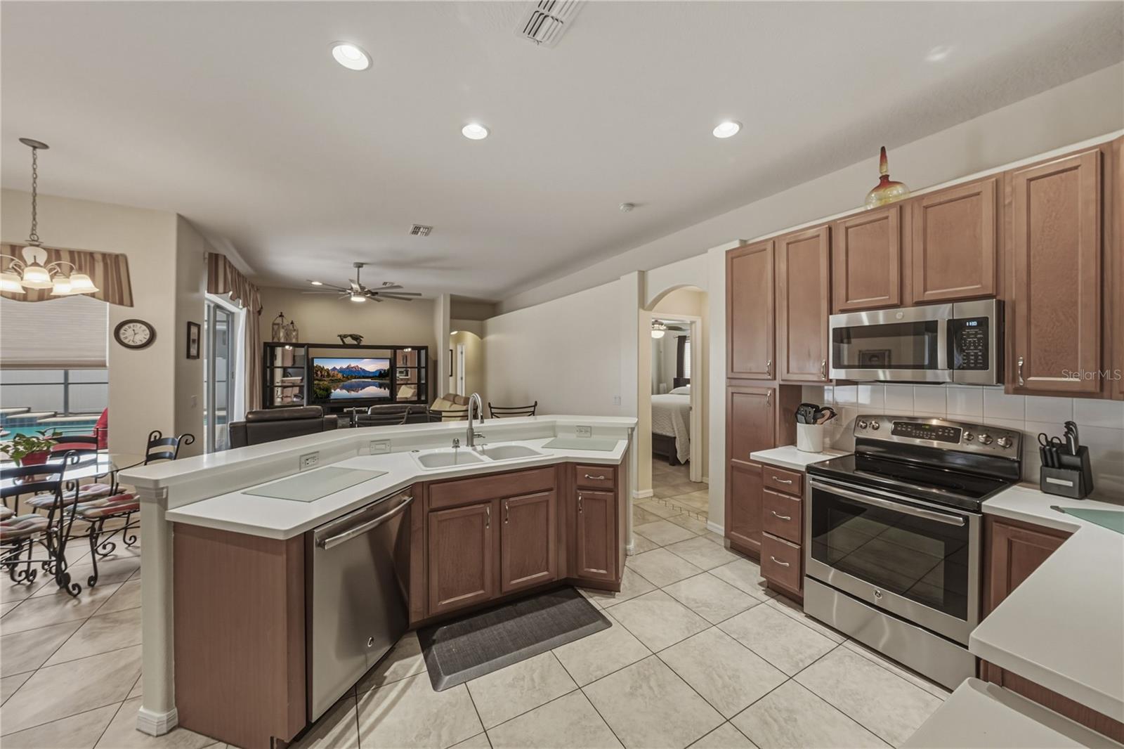 Bright, open-concept kitchen flowing into a cozy breakfast nook and spacious family room, perfect for everyday living and entertaining with direct access to the pool.