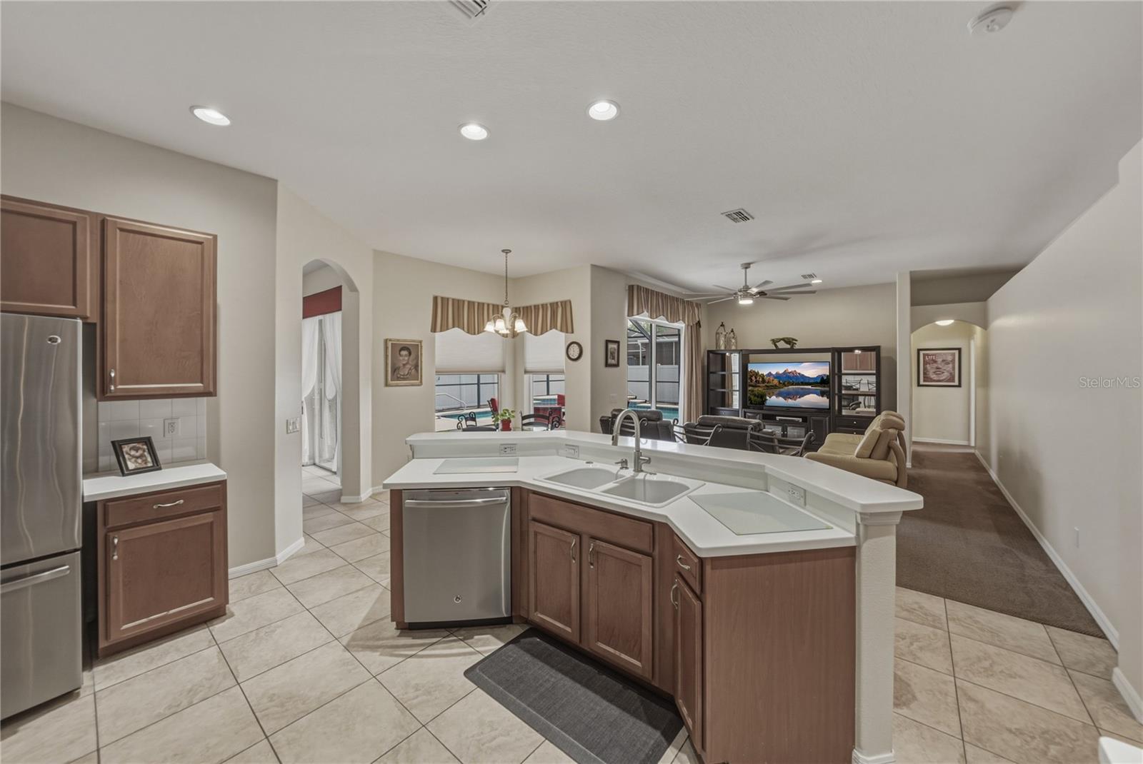 Bright, open-concept kitchen flowing into a cozy breakfast nook and spacious family room, perfect for everyday living and entertaining with direct access to the pool.