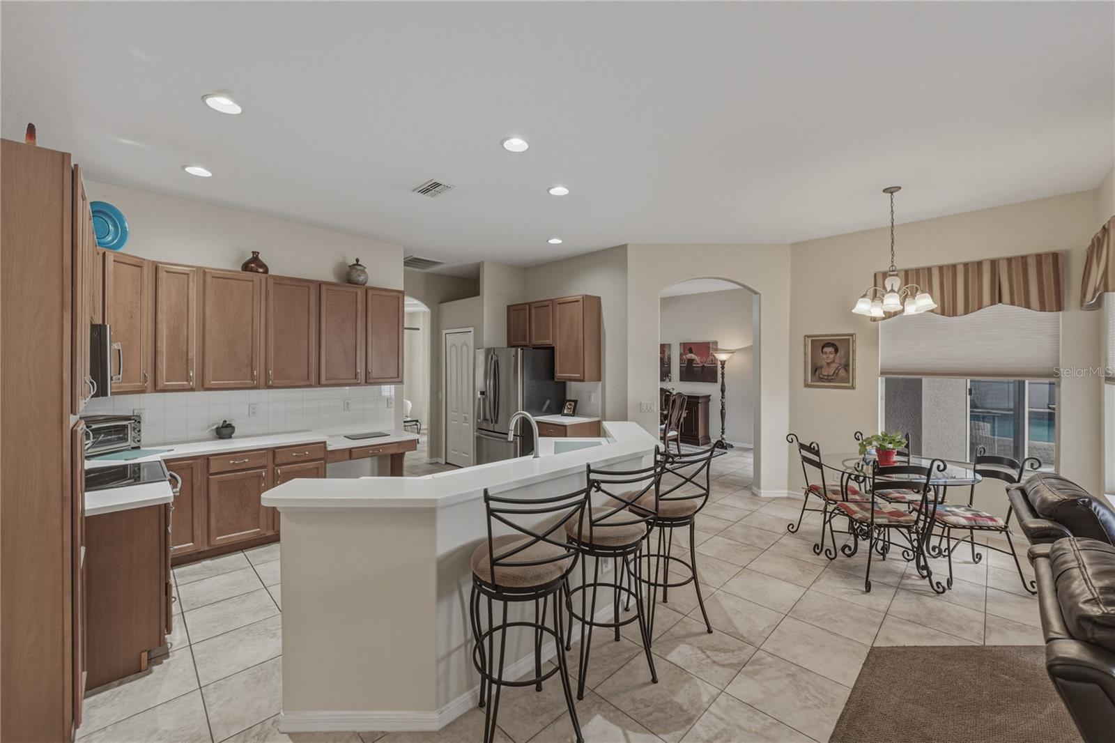 Bright, open-concept kitchen flowing into a cozy breakfast nook and spacious family room, perfect for everyday living and entertaining with direct access to the pool.