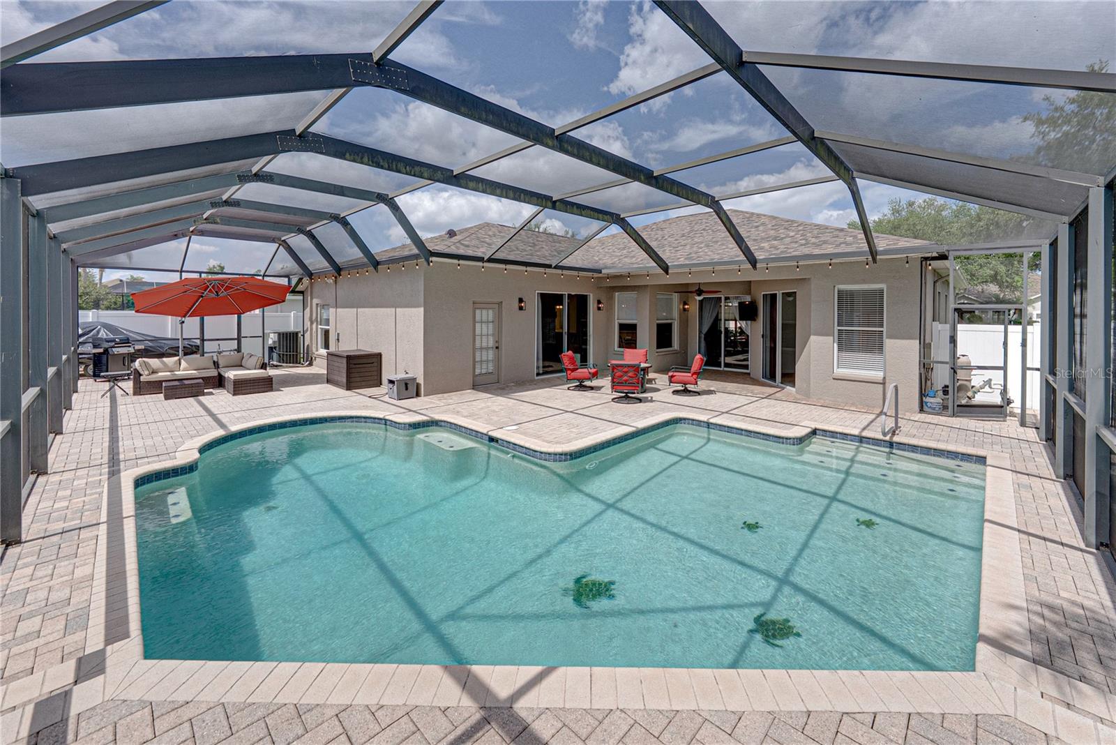 Expansive outdoor living with a large lanai, pool, and lounge area, all set in a low-maintenance backyard designed for effortless Florida living and entertaining.