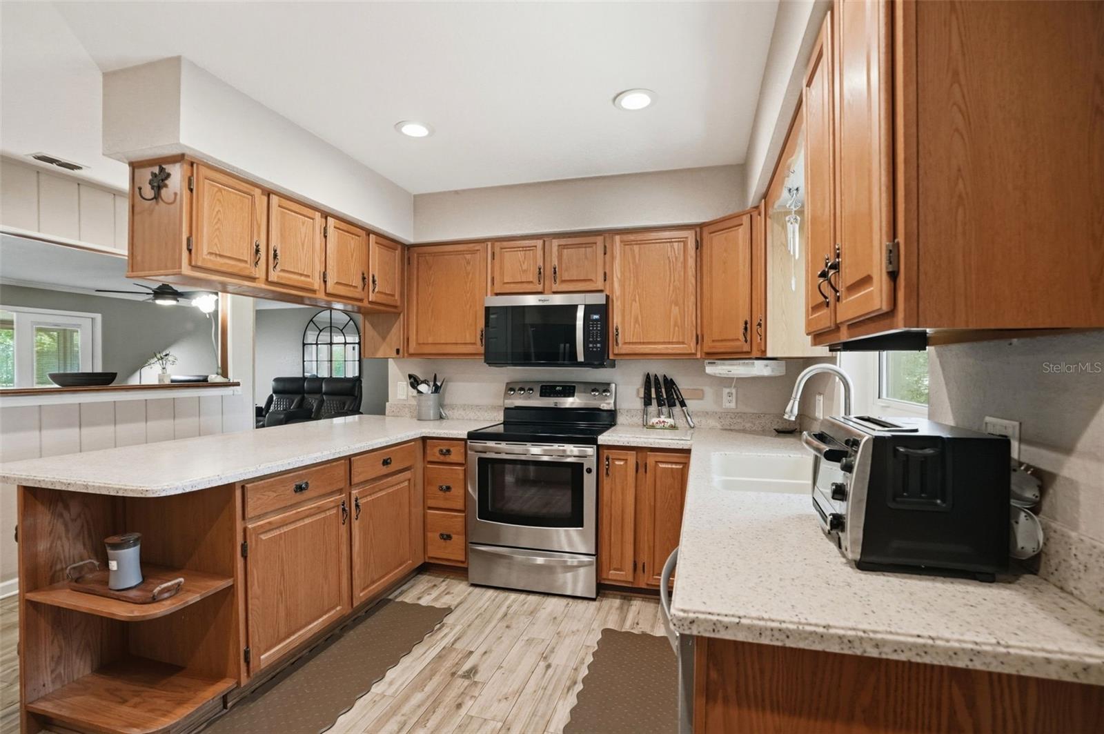 Large U-Shaped Kitchen with Natural Light Window over the Sink, Open to Living Room, Bar Stool Seating Area, Solid Surface Counters and Integral Sink for easy maintenance, and Double Door Pantry Closet