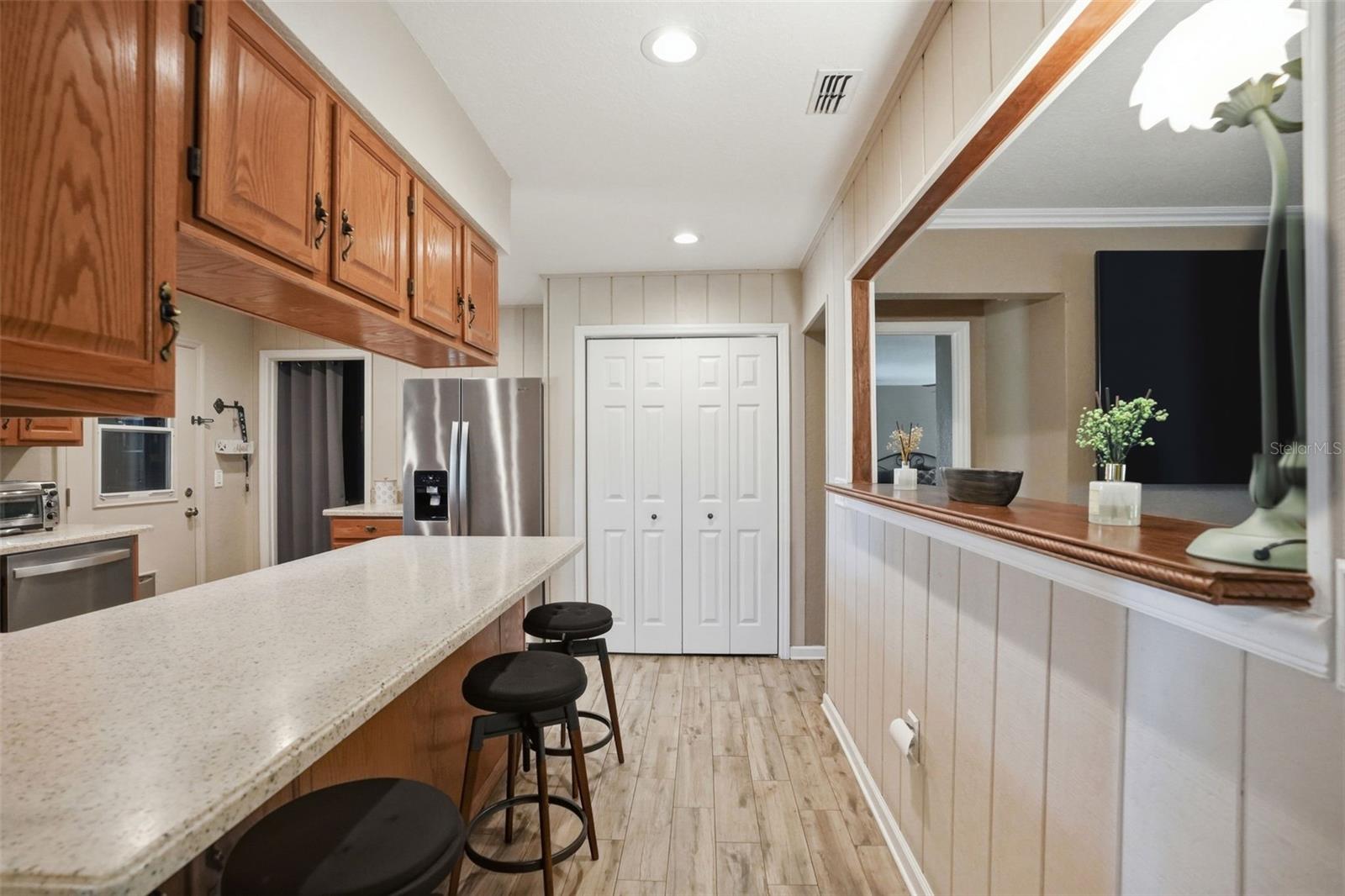 Large U-Shaped Kitchen with Natural Light Window over the Sink, Open to Living Room, Bar Stool Seating Area, Solid Surface Counters and Integral Sink for easy maintenance, and Double Door Pantry Closet