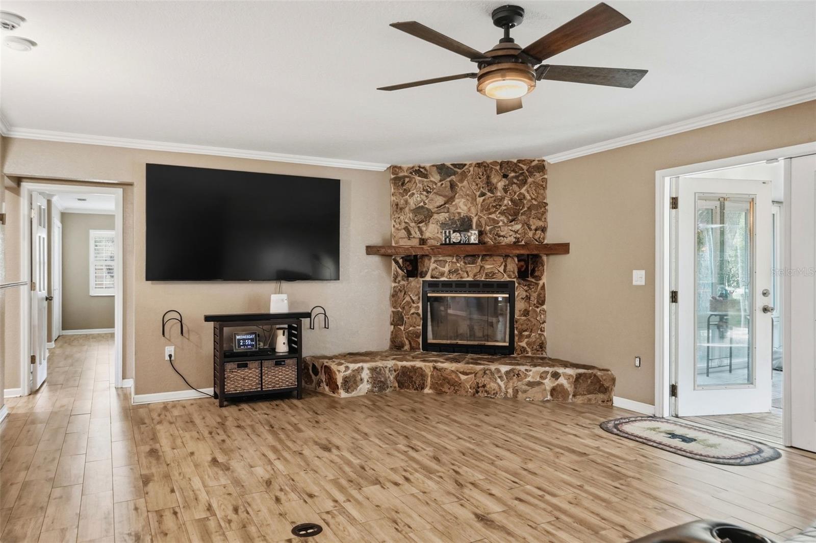 Open Living Room with Wood Burning Stone Fireplace, Double French Doors to heated and cooled Sunroom, open to Dining Room and Kitchen, with wood look tile floors for easy maintenance