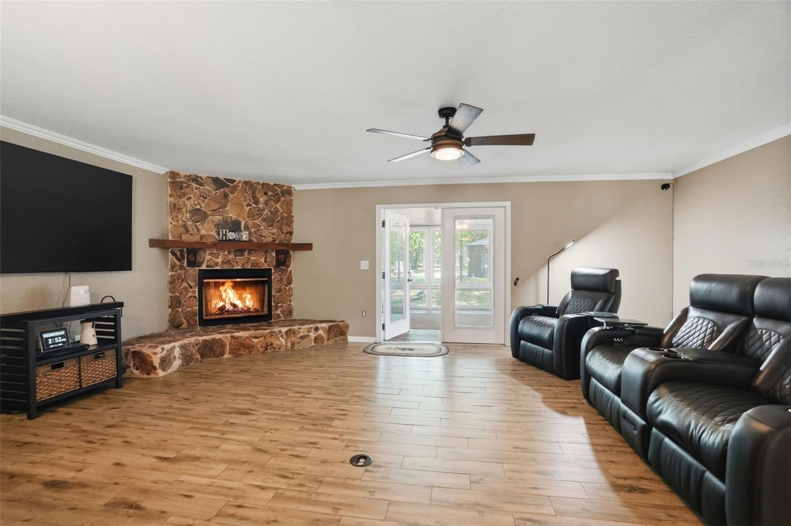 Open Living Room with Wood Burning Stone Fireplace, Double French Doors to heated and cooled Sunroom, open to Dining Room and Kitchen, with wood look tile floors for easy maintenance