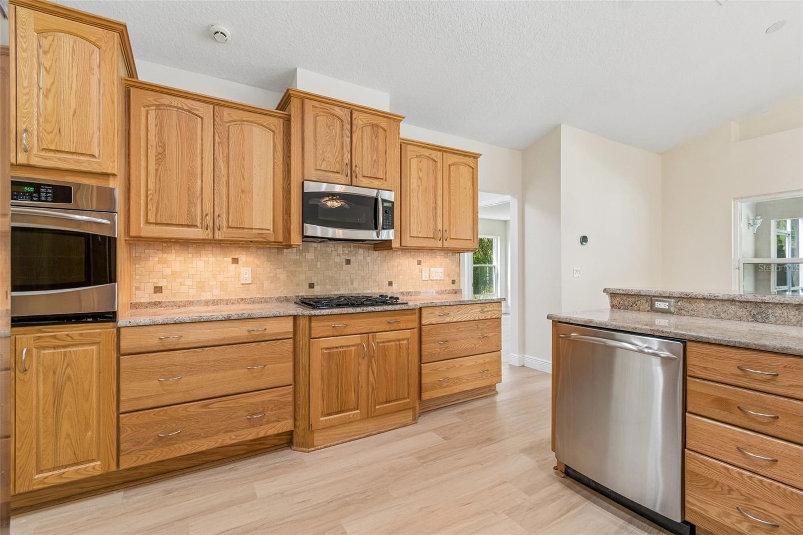 All wood cabinets, roll out drawers, travertine backsplash and stone counters round out a gorgeous and functional kitchen!