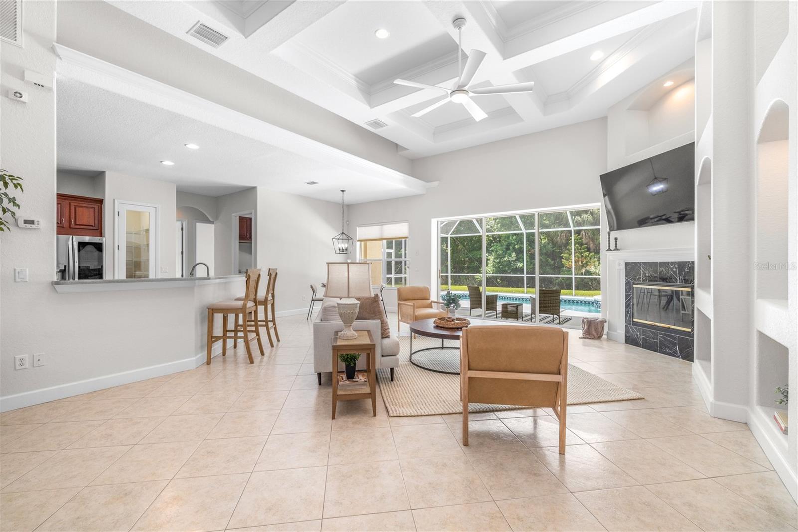 Expansive open-concept living space with custom ceiling details and seamless indoor-outdoor flow through pocket sliding glass doors