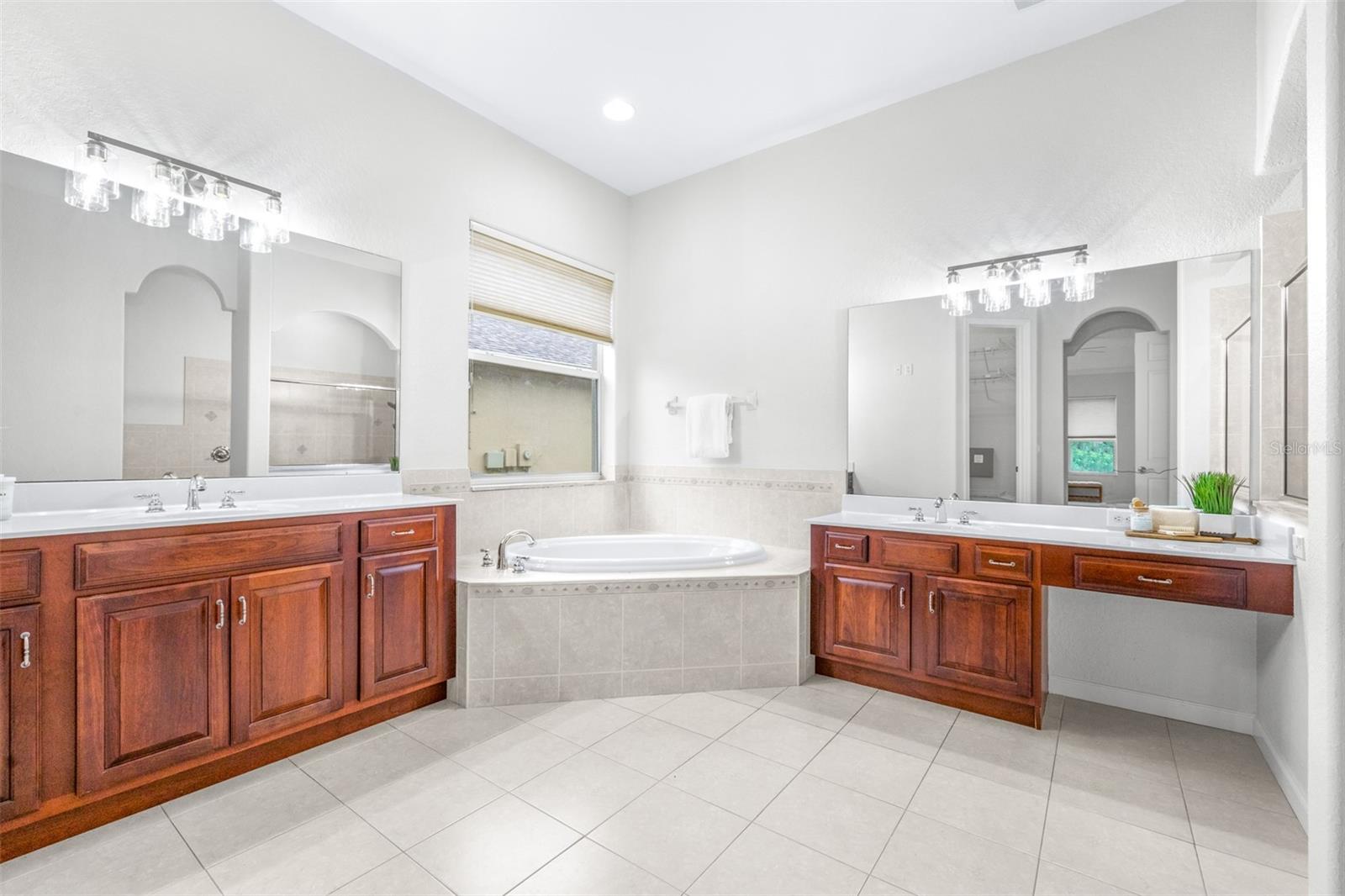 Dual vanities with jetted tub and elegant lighting throughout