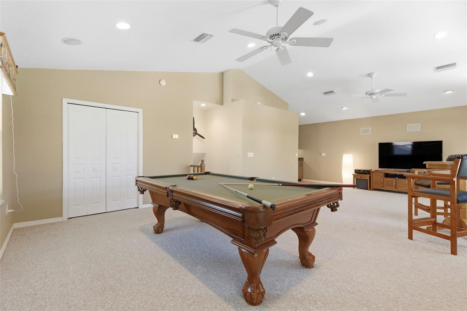 Expansive bonus room designed for entertaining and relaxation, featuring soaring ceilings, abundant natural light, and ample space for a game room, media lounge, or private retreat. Complete with a pool table and room for additional seating or activities, this versatile space is perfect for hosting, unwinding, or creating the ultimate entertainment zone.