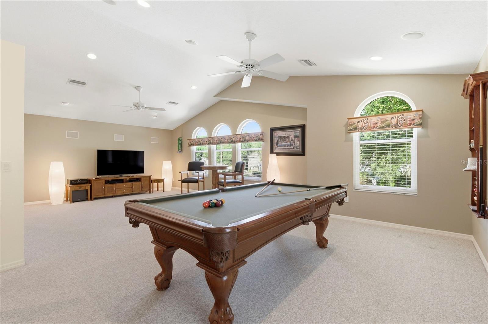 Expansive bonus room designed for entertaining and relaxation, featuring soaring ceilings, abundant natural light, and ample space for a game room, media lounge, or private retreat. Complete with a pool table and room for additional seating or activities, this versatile space is perfect for hosting, unwinding, or creating the ultimate entertainment zone.