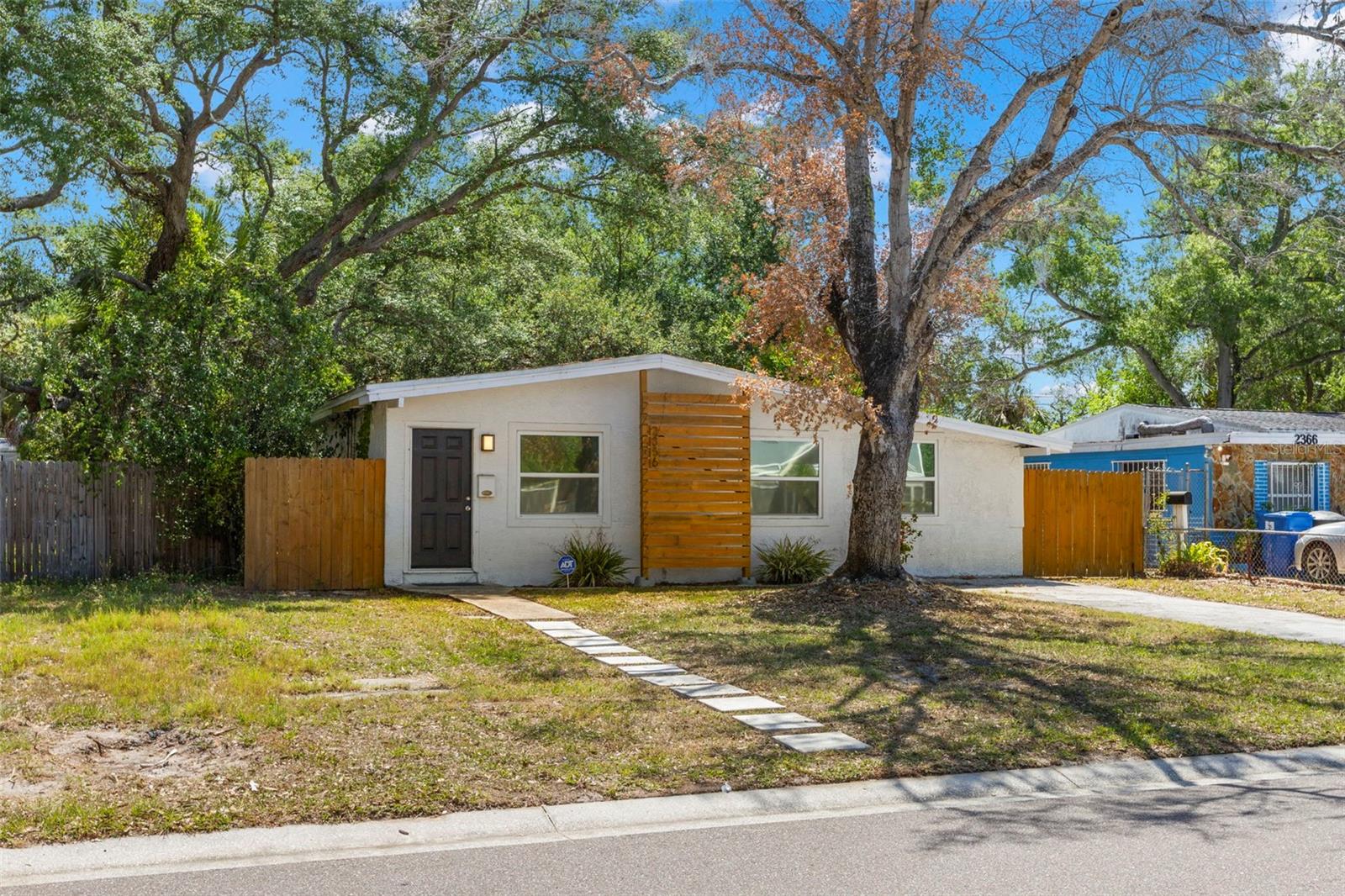 Stylish mid-century-inspired exterior with modern wood accent detailing and mature shade trees.