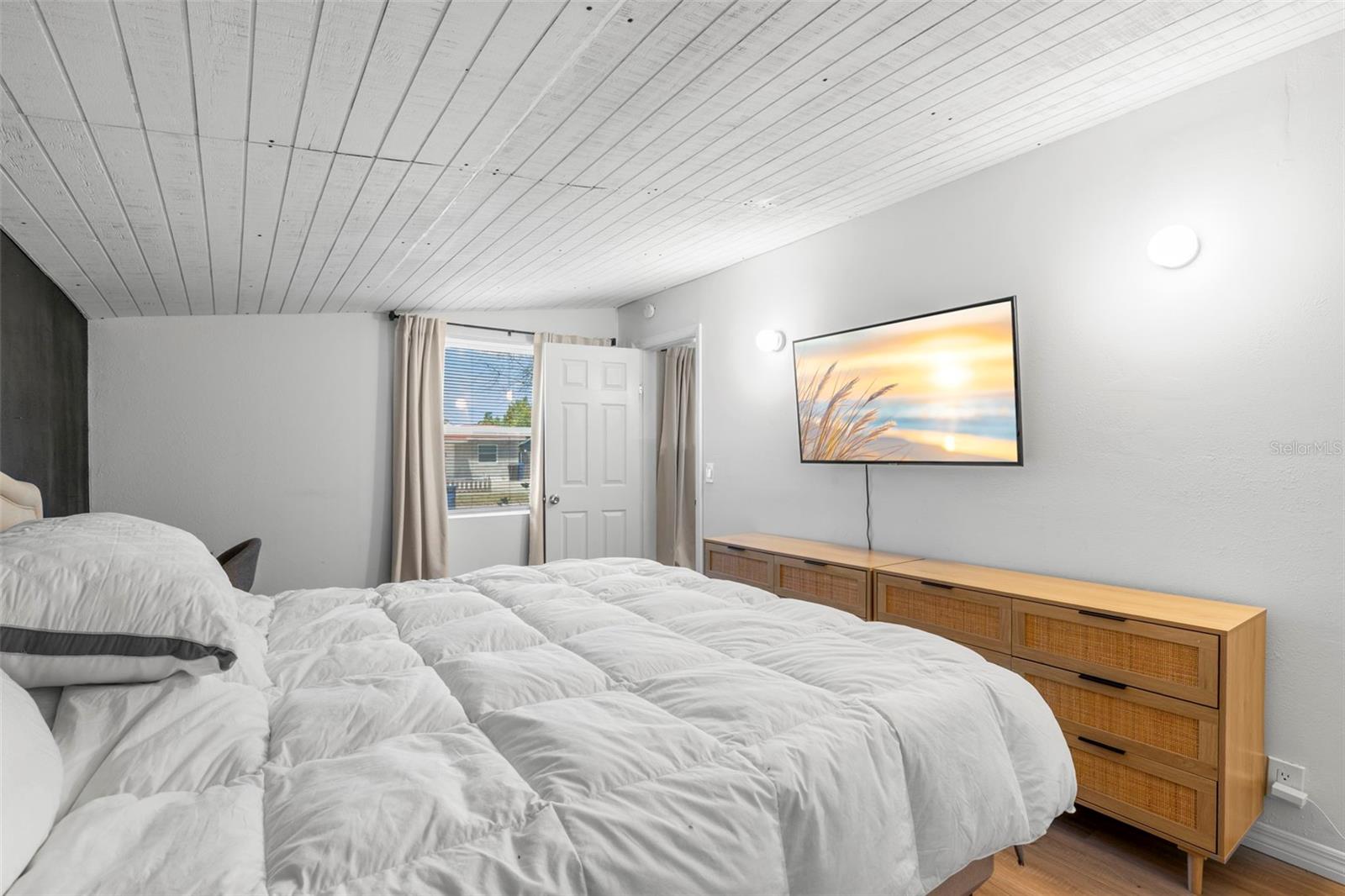Primary bedroom features a vaulted wood-plank ceiling, statement accent wall, and built-in closet.
