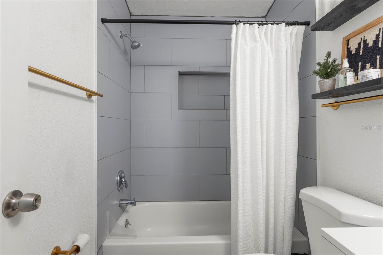 Tub/shower combination features built-in niche storage and sleek contemporary finishes.