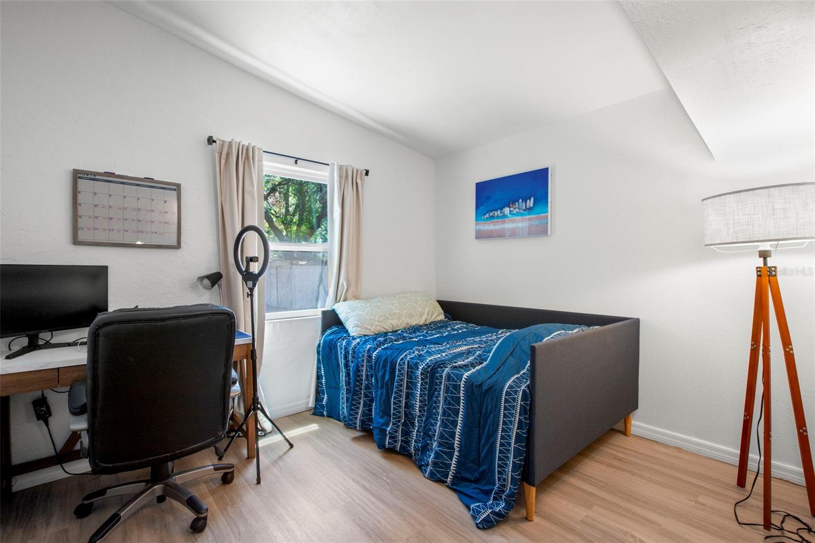 Bright third bedroom features a vaulted ceiling, laminate flooring, neutral finishes, and a built-in closet.