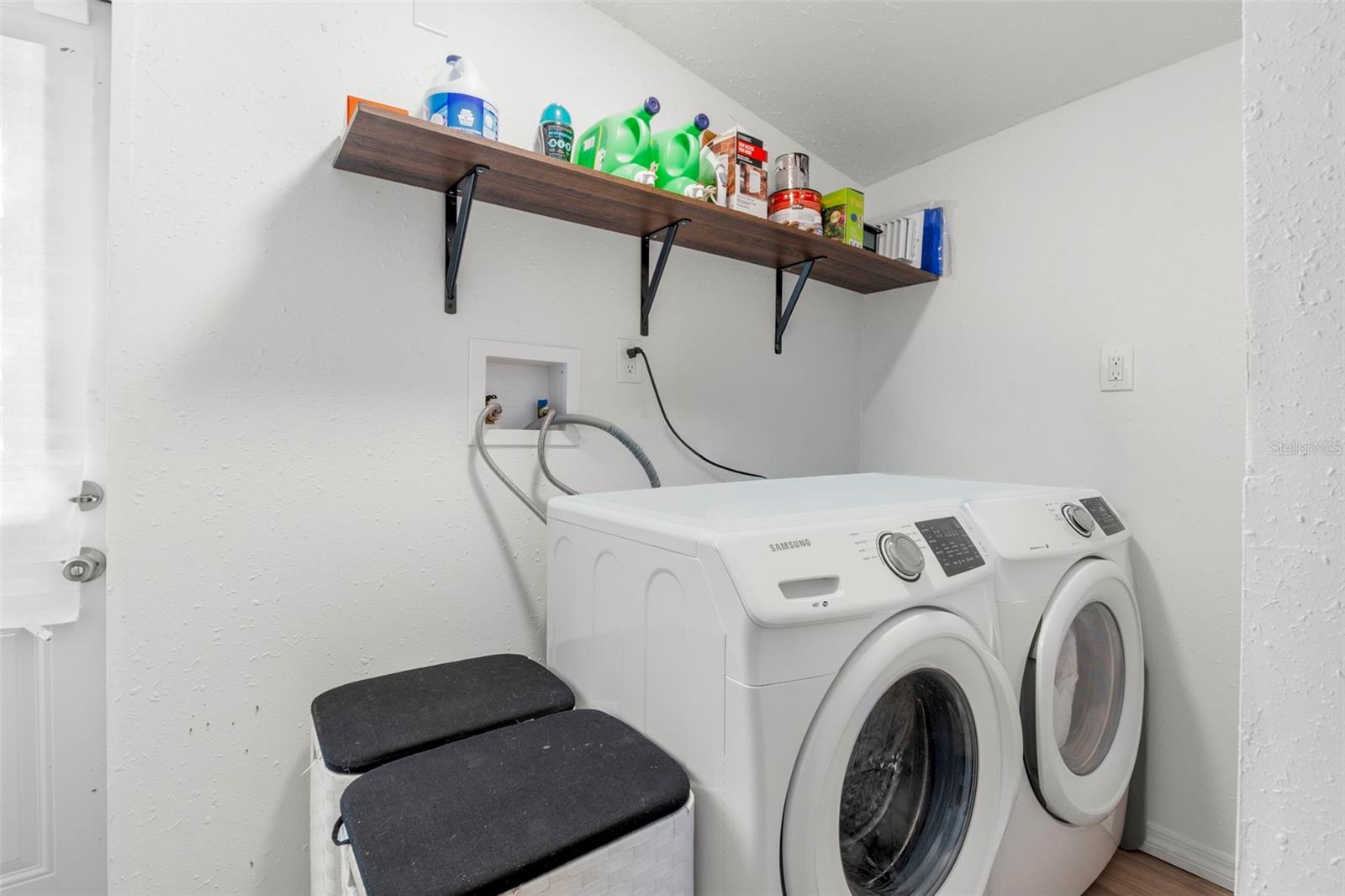 Dedicated interior laundry room with full-size washer and dryer and added shelving for storage.
