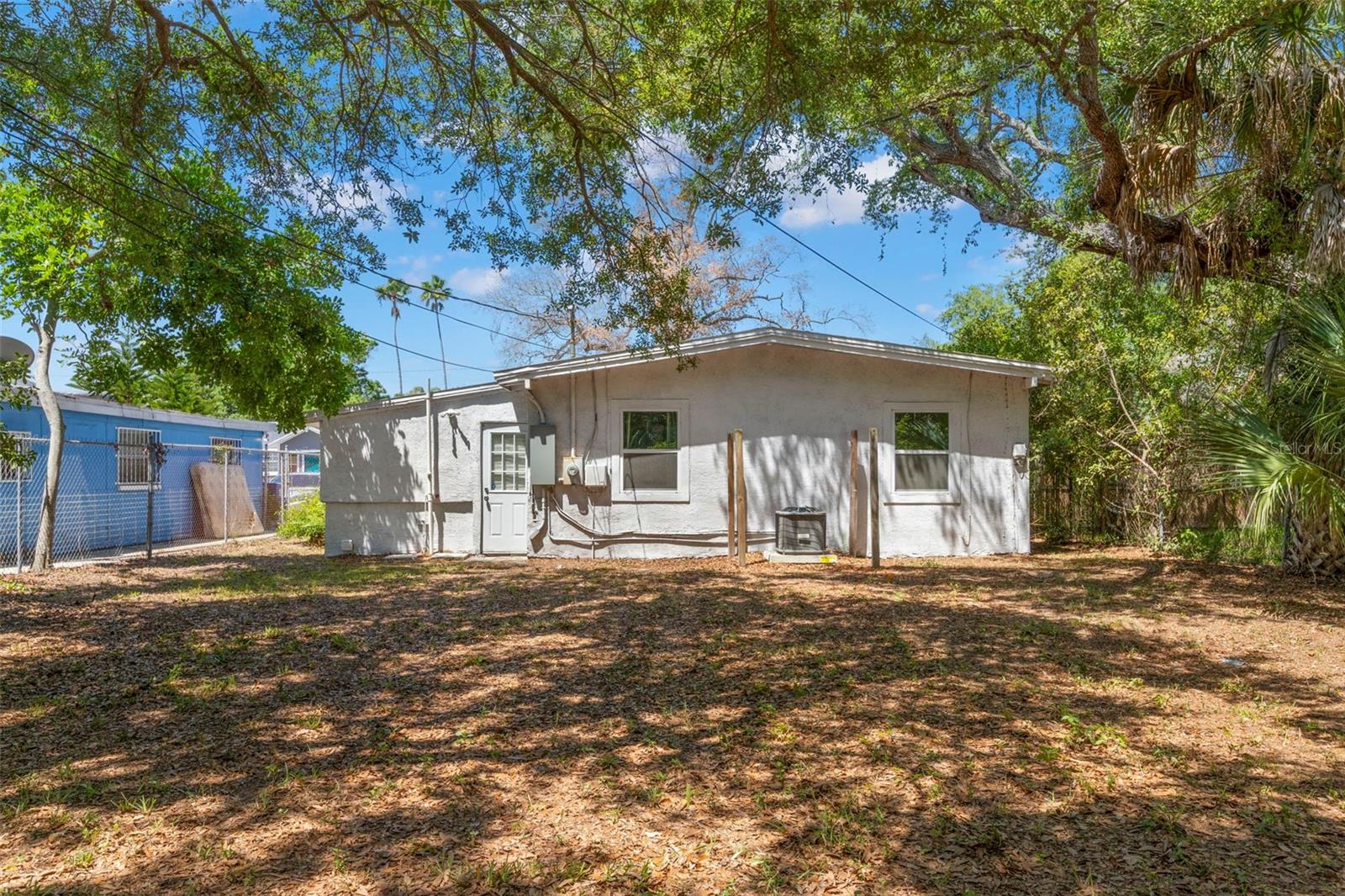 Expansive fenced yard shaded by mature trees creates a private outdoor setting.