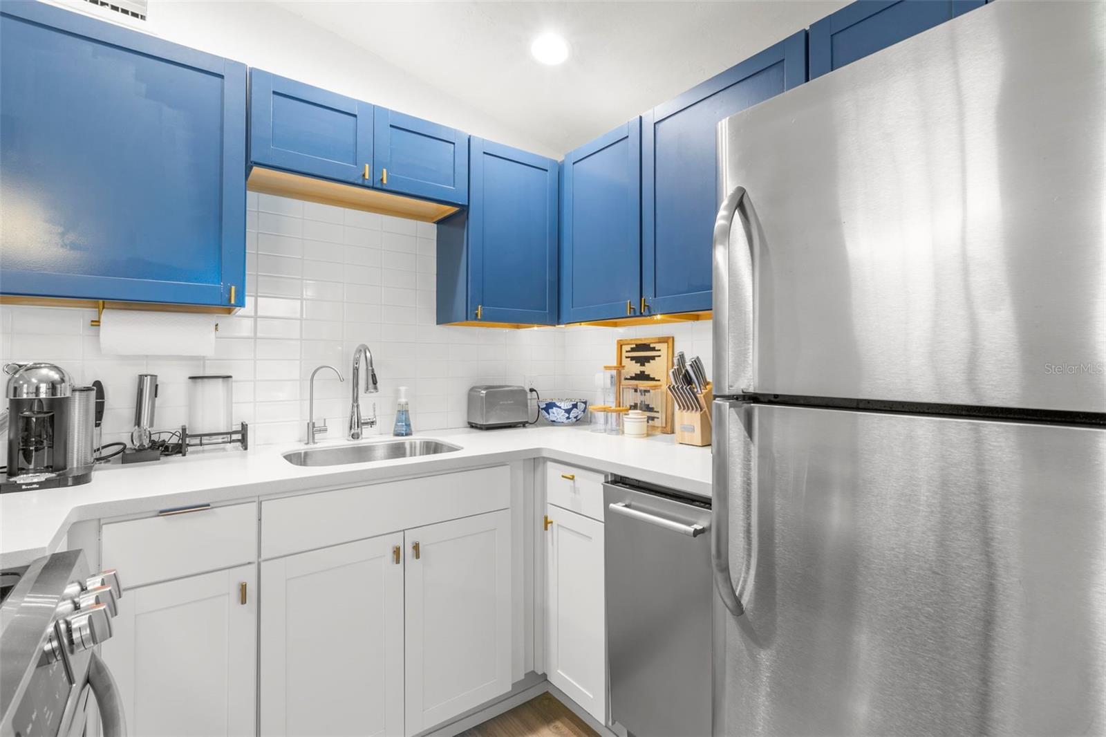 Bold two-tone cabinetry, gold hardware, and designer pendant lighting add elevated contemporary style.