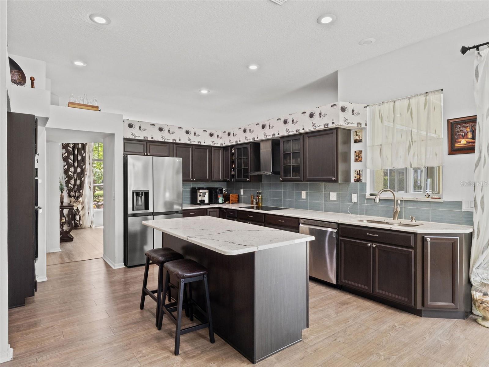Spacious kitchen layout with oversized island seating, recessed lighting, and a functional flow into adjacent living and dining areas.