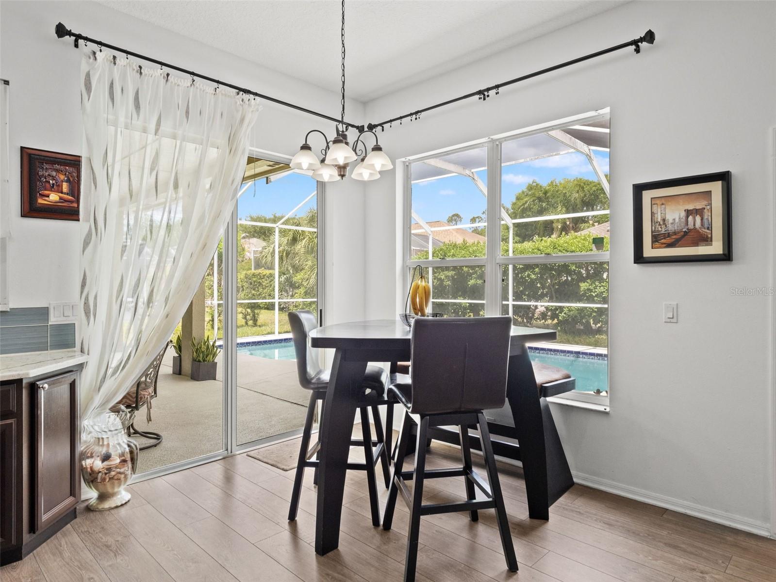 Sunlit dining nook overlooking the pool area, featuring large windows and direct access to the lanai—perfect for casual meals with a view.