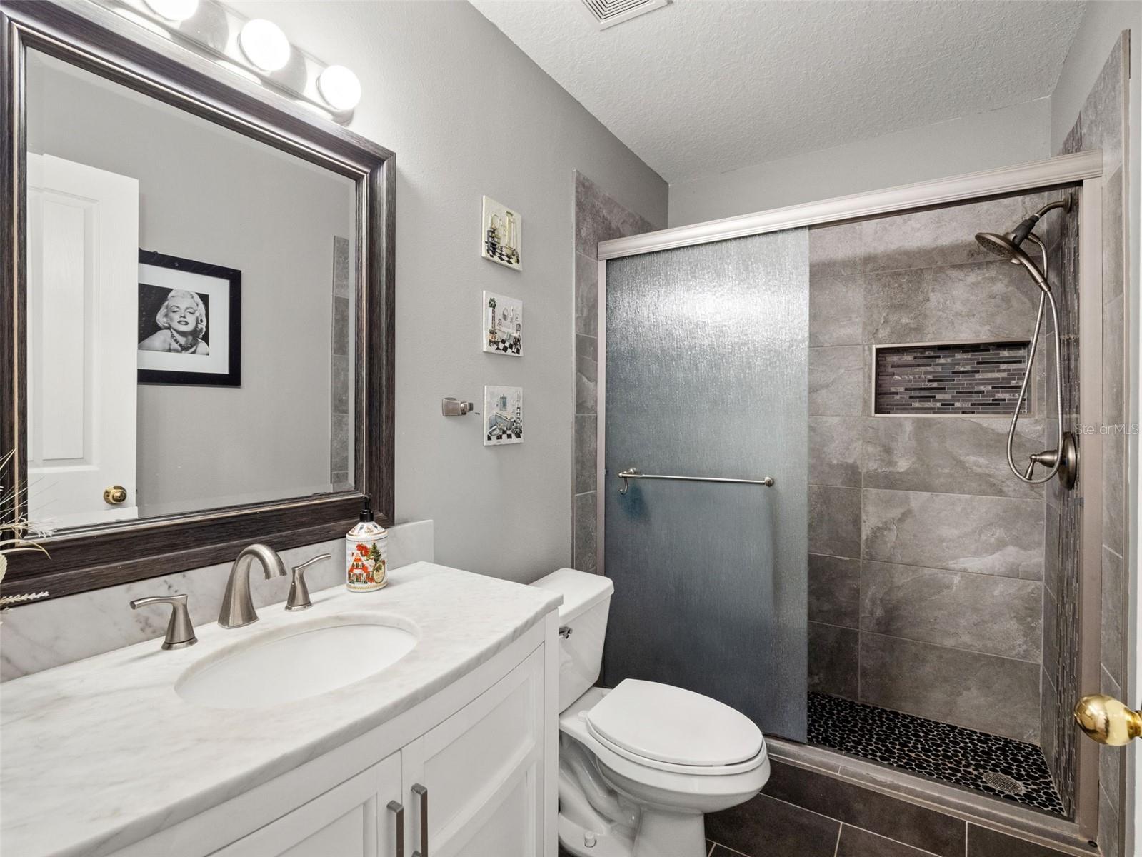 Stylishly updated bathroom with modern tile shower, glass enclosure, and sleek vanity, offering a clean and contemporary feel.