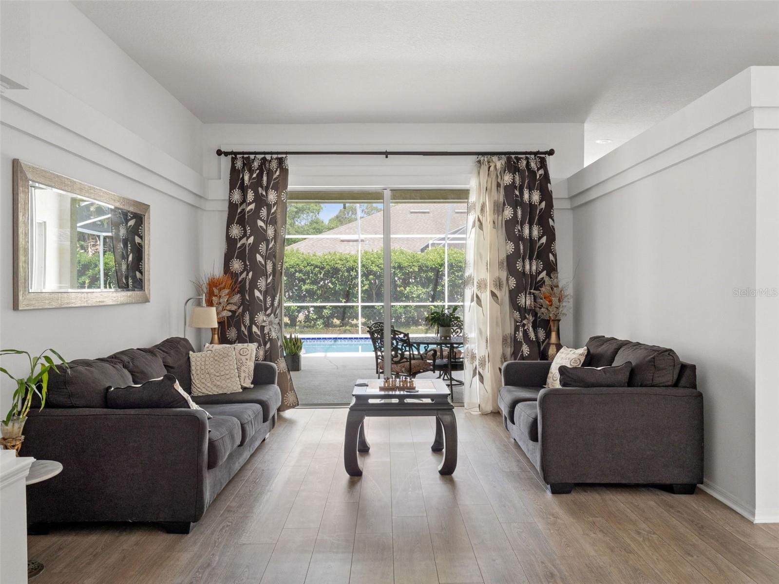 Inviting living area with large sliding glass doors that open to the lanai and pool, creating a bright space perfect for relaxing or entertaining.