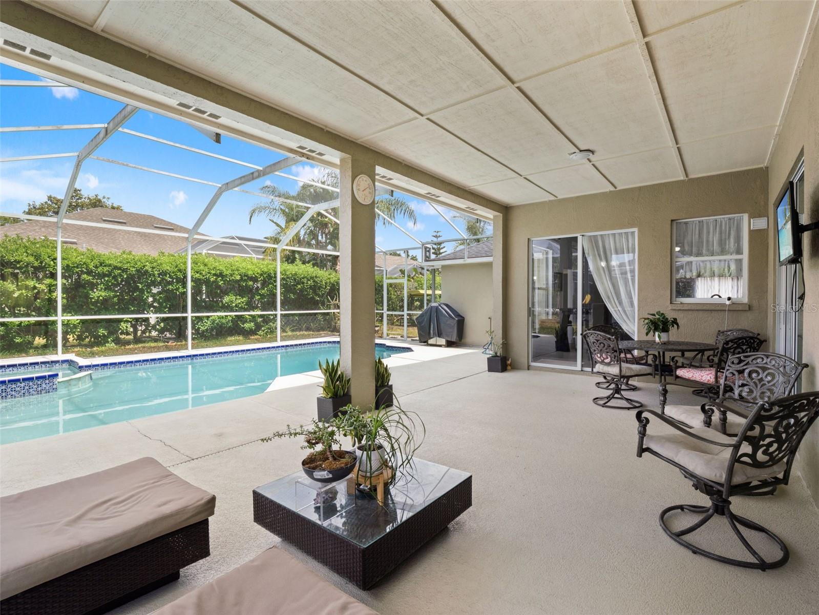 Expansive covered outdoor living space with ceiling panels for shade and comfort, offering seamless indoor-outdoor flow.