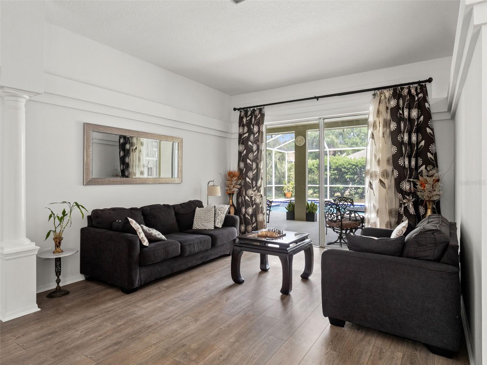 Bright and welcoming living space with large sliding glass doors that frame views of the covered lanai and pool, filling the room with natural light.