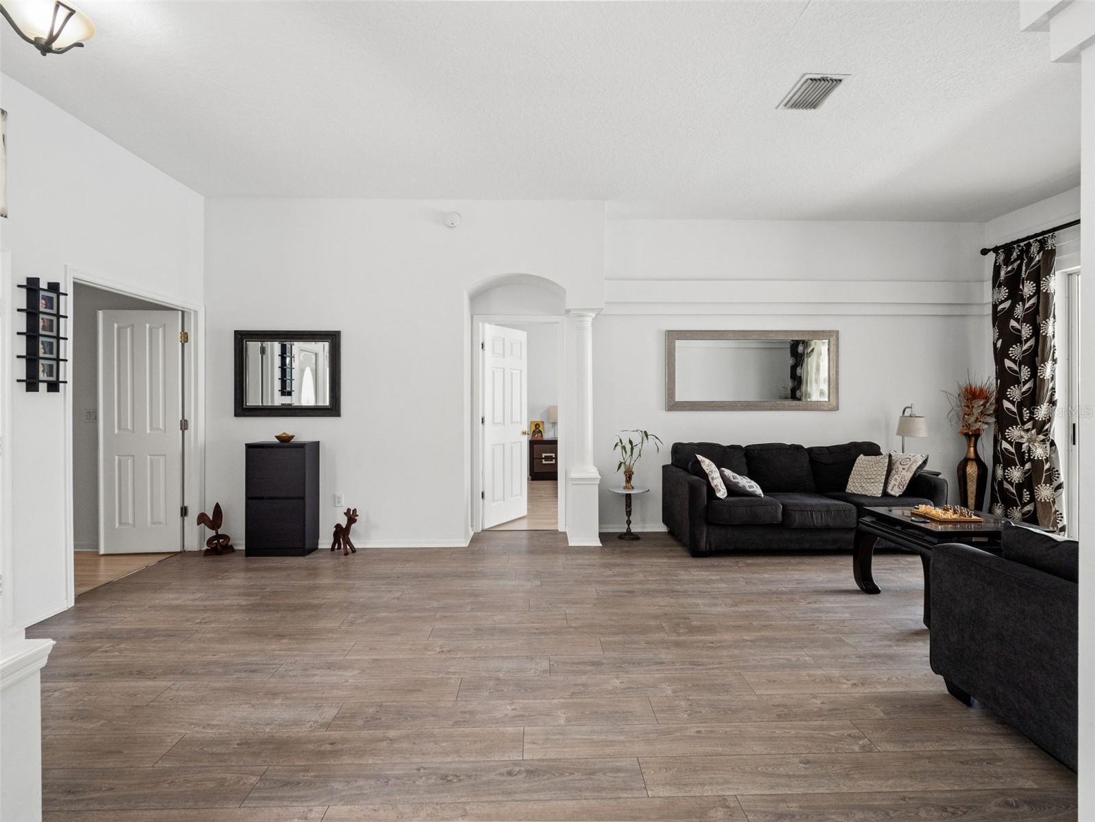 Expansive open living area with wood-style flooring and neutral finishes, offering plenty of room for both relaxing and entertaining.