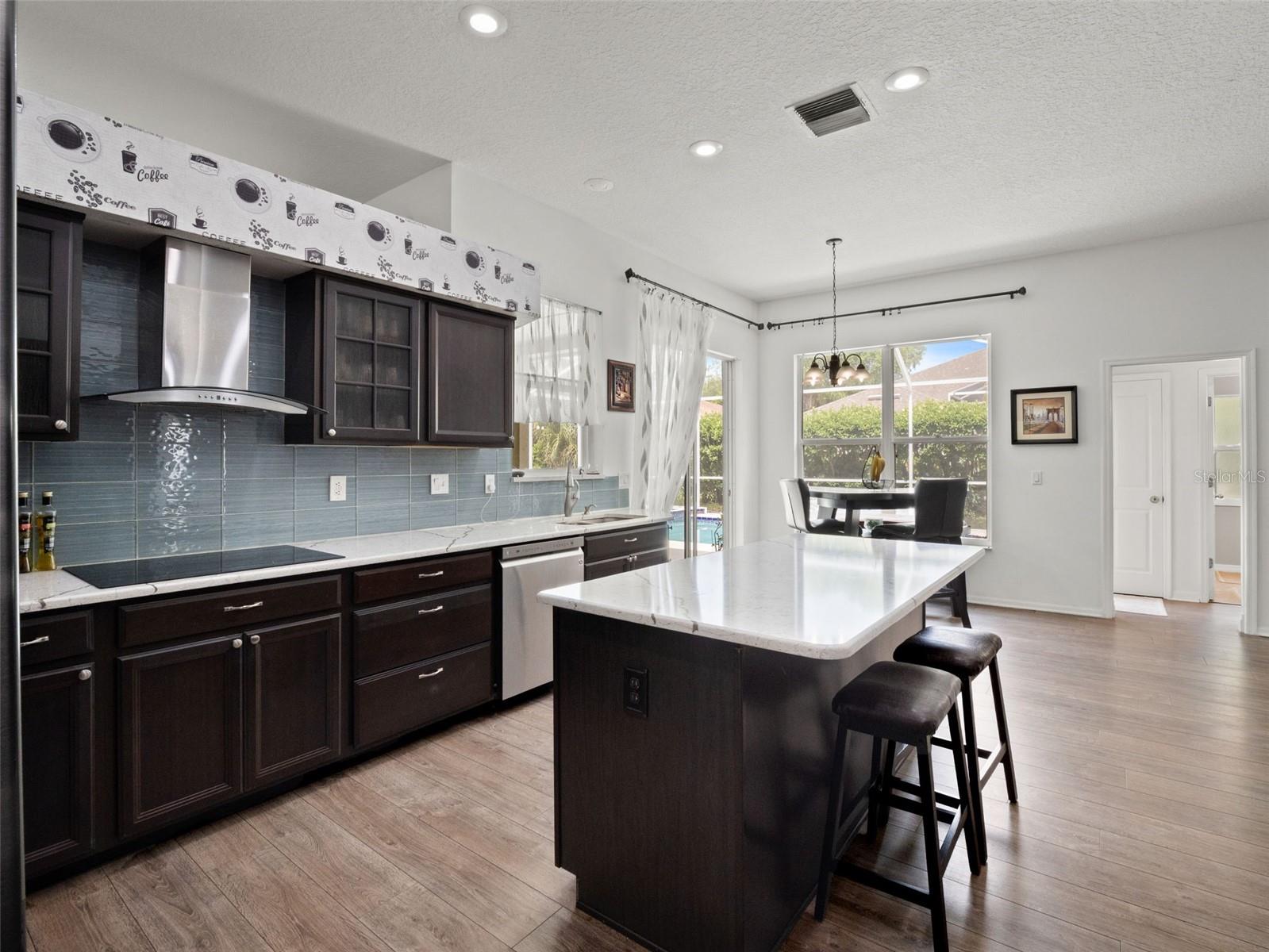 Open-concept kitchen and dining space featuring a large center island, sleek countertops, and abundant cabinetry, seamlessly connecting to the breakfast nook.