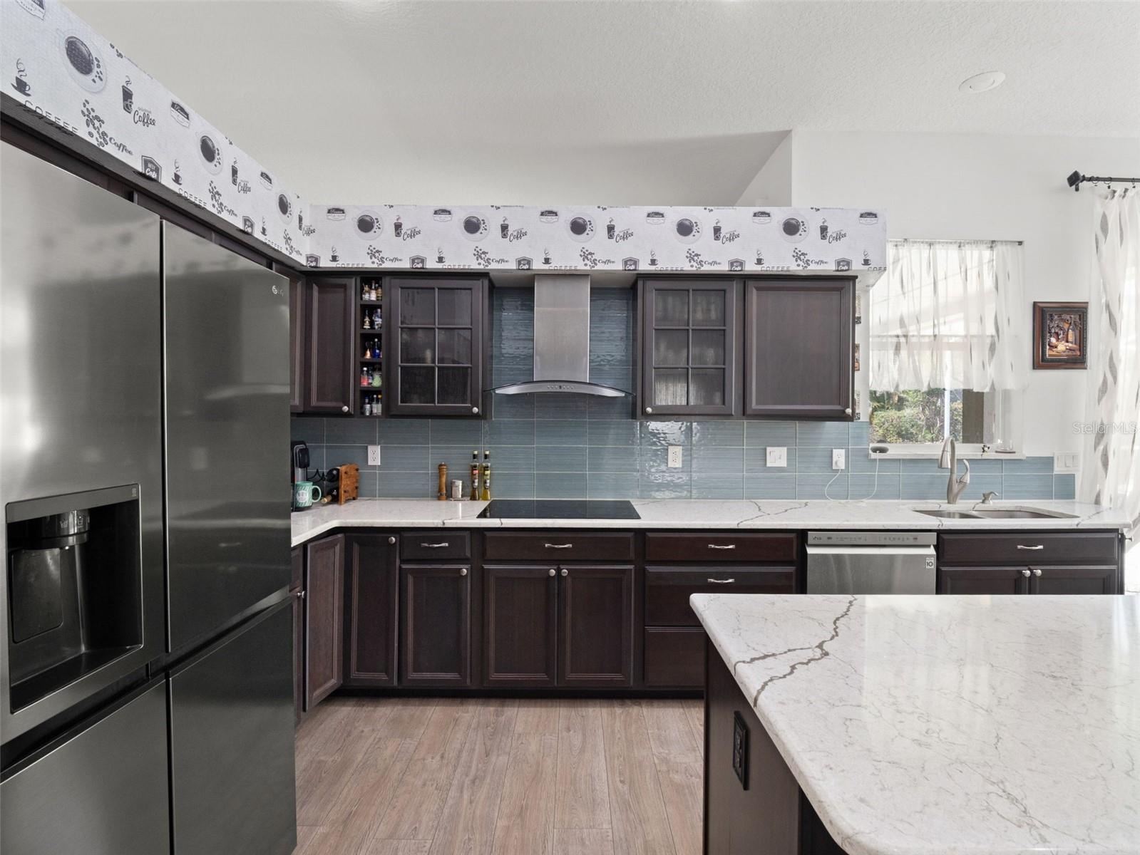 Well-designed kitchen with stainless steel appliances, tile backsplash, and ample prep space, ideal for everyday cooking and hosting.